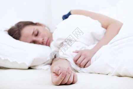 年轻女士睡在床上得安稳把注意力放在床垫上伸的手休息睡着了羽绒被图片