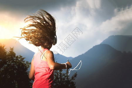 快乐的带着头发小女孩在风中吹着头发用播放器和耳机听音乐微笑请享用图片