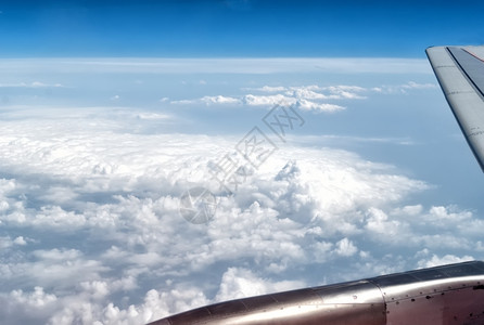 蓝云中的飞机翅膀平流层白色的蓝背景图片