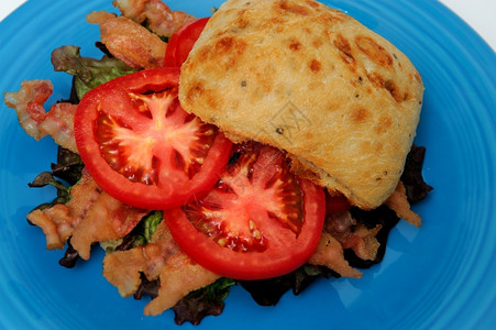 油炸已知绿色Ciabatata卷上的一个盘子摆着叫做BLT的番茄三明治和烤菜背景图片