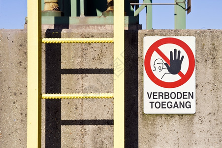 阴影肮脏的在一个工厂混凝石柱上一个梯子和没有进入警告信号标志工业的图片