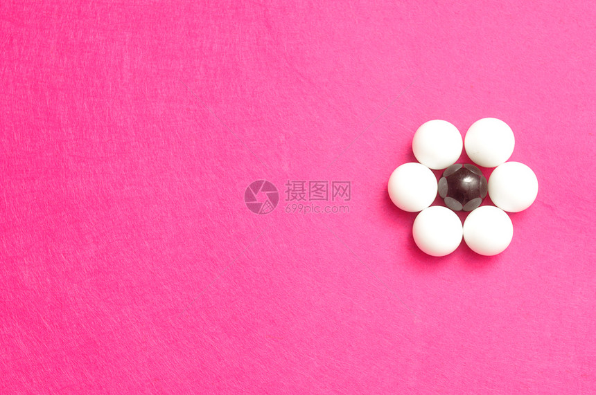 象征一种圆形的以粉红背景孤立的花朵形状包装白球和黑图片