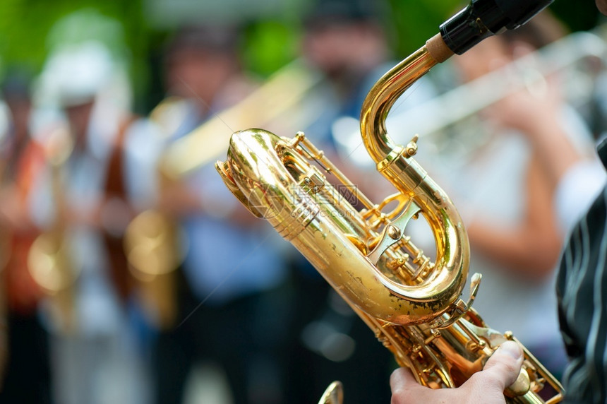 玩街头艺人BaritoneSaxophone播放器与他的团体进行街头表演音乐家图片