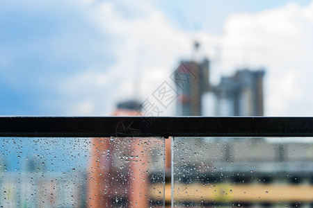 城市下雨旅行玻璃阳台雨天和蓝色空背景下建筑的雨滴图片