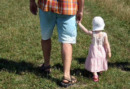 父亲牵着小女孩在户外行走图片