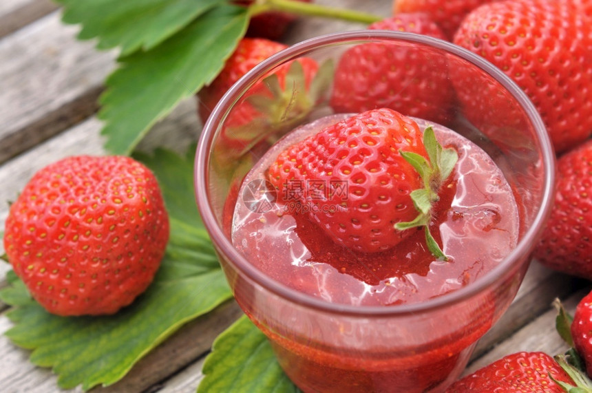 甜的叶子草莓果酱罐头来自树叶和木制桌上的其他草莓红色图片