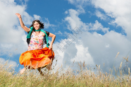 女士妇嬉皮在草地上跳跃户外夏天图片