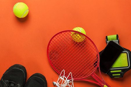 耳机网球红背景智能手机和网球游戏躺着拍图片