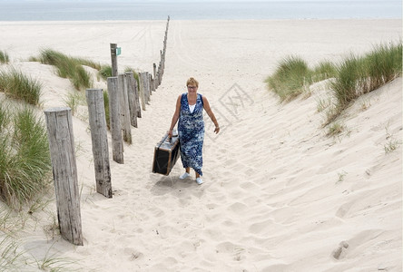 假期金发从海滩上走来去的妇女手提箱木头图片