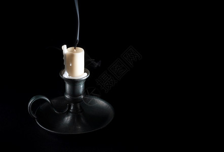 黑色熄灭的蜡烛在旧锡烛台和黑底烟雾中熄灭的蜡烛巴斯塔古董老的背景
