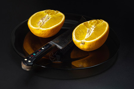黑色的仍带着橙和一把大刀在黑暗盘子上生活着黑底柑橘一种图片
