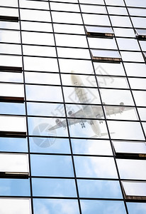 办公室挡板窗口中的客用喷气式反射航空外部的摩天大楼图片