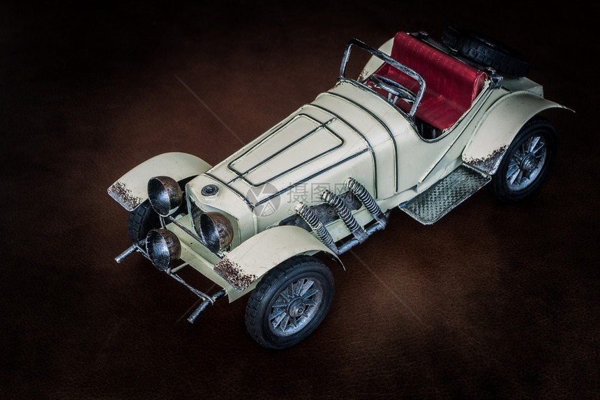 目的怀旧微型棕色皮革衬垫上的古董玩具车图片