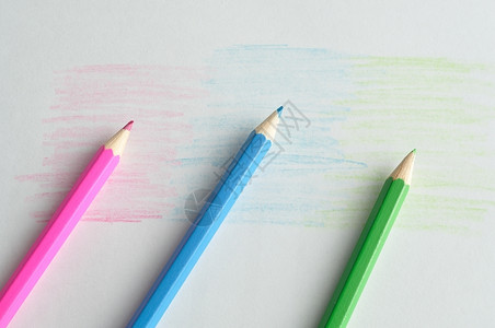 三个彩色铅笔在纸上绘画图片
