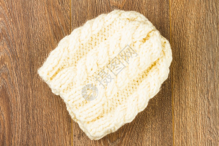 木背景上的白色编织帽温暖的材料棉布图片