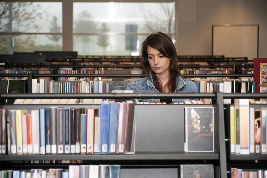 单身的精装书年轻女在公共图书馆用几本架搜索籍的藏室20多岁图片