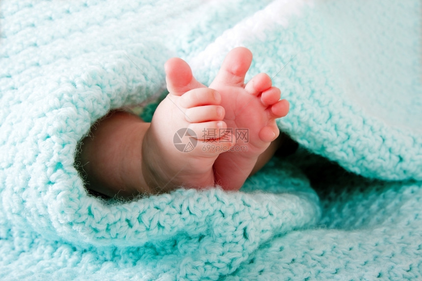 针织的两只可爱小婴儿脚裹在蓝色绿水蜜毯上西班牙裔包裹图片