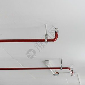 金属水红色的白天花板背景的灭火喷洒器和红管图片