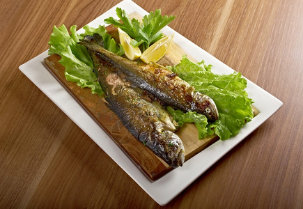 木板上的烤鱼和配菜图片