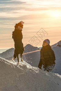 他的可爱年轻边小狗在雪上玩和情妇在特山玩背景图片