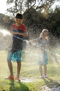 儿童在炎热的天气中玩喷水器机图片
