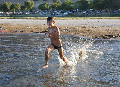 一个男孩在Kinneret湖温水中玩耍滴暖的戏剧图片