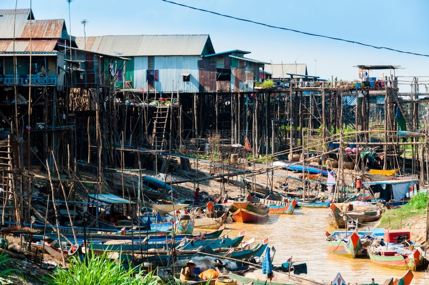 村庄柬埔寨人在河泥土流的中在房石板和木船上建造房屋和木船高架图片