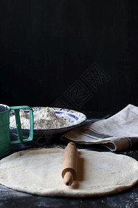 面粉包和比萨饼用黑底的面粉做揉捏一种浇注图片