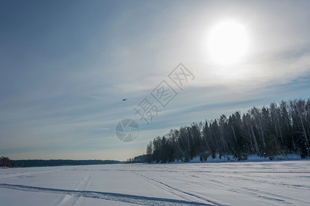 寒冬风景背光中直升机阳照耀着积雪的河水冬天景观白雪皑图片
