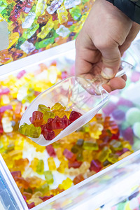 儿童手从糖果店的展示品中摘果冻糖用贴上多彩的果胶甜点图片