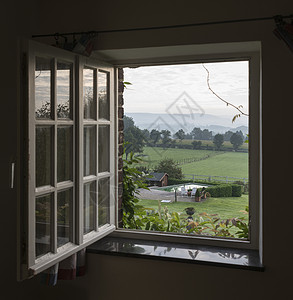 透过窗口看到以风景和山丘为背的草牧场自然图片