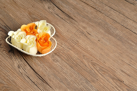 装满橙色和白玫瑰肥皂的心形铁丝篮子木制的花瓣身体图片