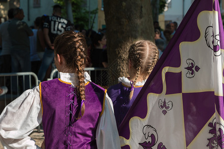 紫色旗帜游行期间穿着制服辫子发型的小女孩附近紫罗兰色旗游行期间穿着制服辫子发型的小女孩附近紫罗兰色旗编织的帜背景