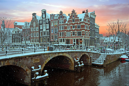 日落时冬天荷兰的雪季阿姆斯特丹水白雪皑屋图片