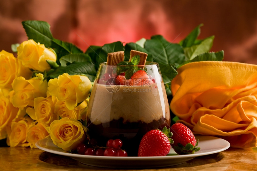 在玫瑰背景前有浆果的巧克力栗子甜瓜奶油的点图片