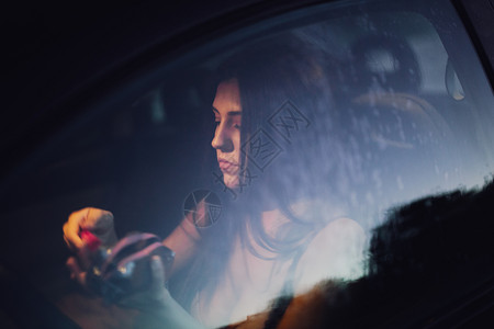 日落时年轻妇女在汽车内化妆魔法里面下雨背景图片