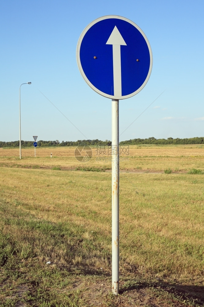 简单的路边蓝色交通标志上的白箭头圆形圈图片
