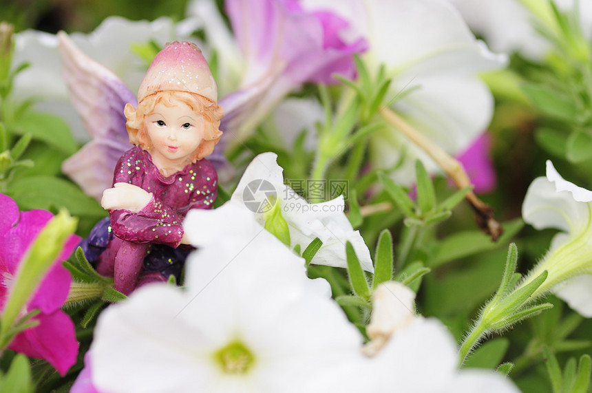 装饰微笑在白色和粉红的花朵中展出一个仙女的雕像矮牵牛图片
