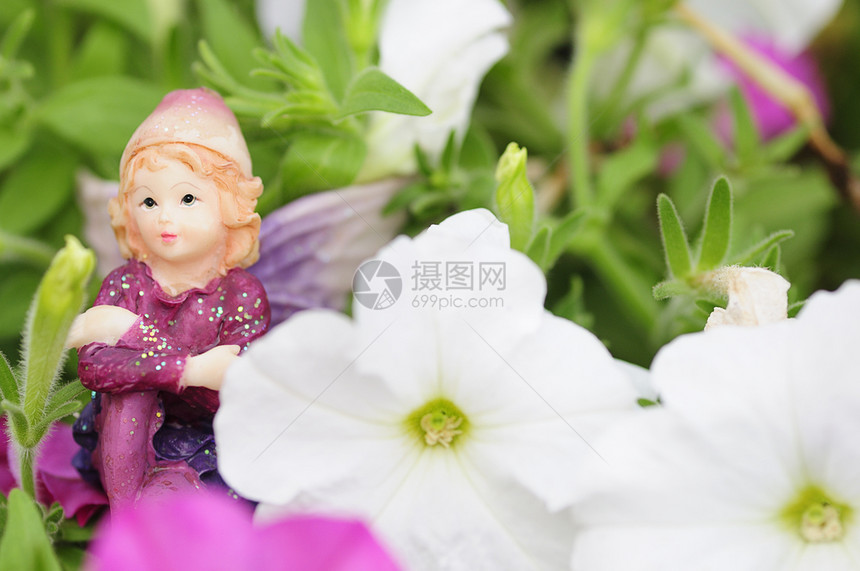 在白色和粉红的花朵中展出一个仙女的雕像白色坐着美丽图片