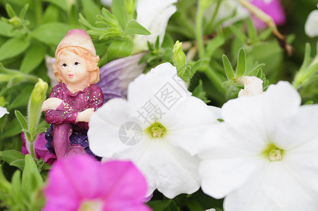 一种幻想可爱的在白色和粉红的花朵中展出一个仙女的雕像图片