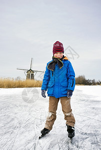典型的在荷兰风景中冰冻运河的面上幼儿滑冰和微笑在摄像机里男生冷冻图片