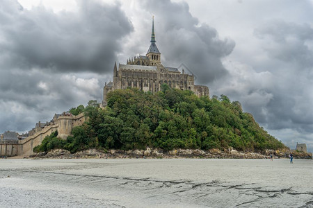 诺曼底修道院在多云的天气中吸引度假旅游圣米歇尔山行浪潮背景图片