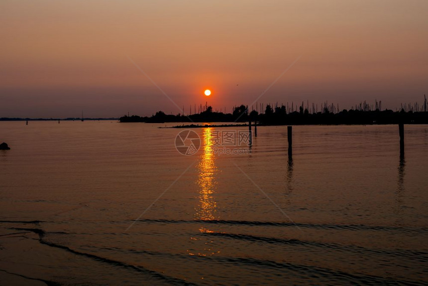 Hellevoetsetsluis港的日落与挂在轮光底背面和天空红橙色船海岸图片