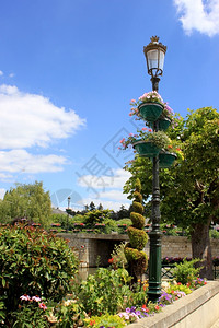 开花园丁城市在蓝天和云彩背景的公园中有花朵笼罩在灯柱上图片