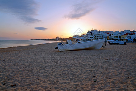户外水日落时在ArmacaodePera海滩上的传统渔民船运输图片