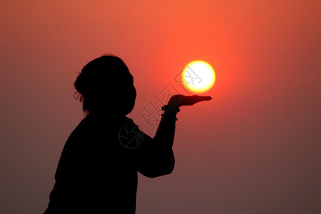 太阳在女手上日出时握太阳的脚影闲暇旅行美丽的图片