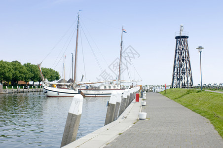 内塞尔旺在荷兰IJsselmeer海岸的Enkhuizen港口入内一艘巨大的平底海船树木信标帆背景