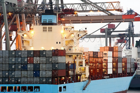 码头一艘大型集装箱船在黎明时由高架起重机在工业港口卸货后勤巨大的图片