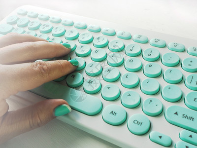 明亮的白色和蓝键盘上白桌子的有蓝色修指甲型女手写导向器图片