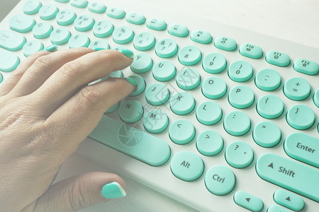 明亮的白色和蓝键盘上白桌子的有蓝色修指甲型女手办公室撰写图片